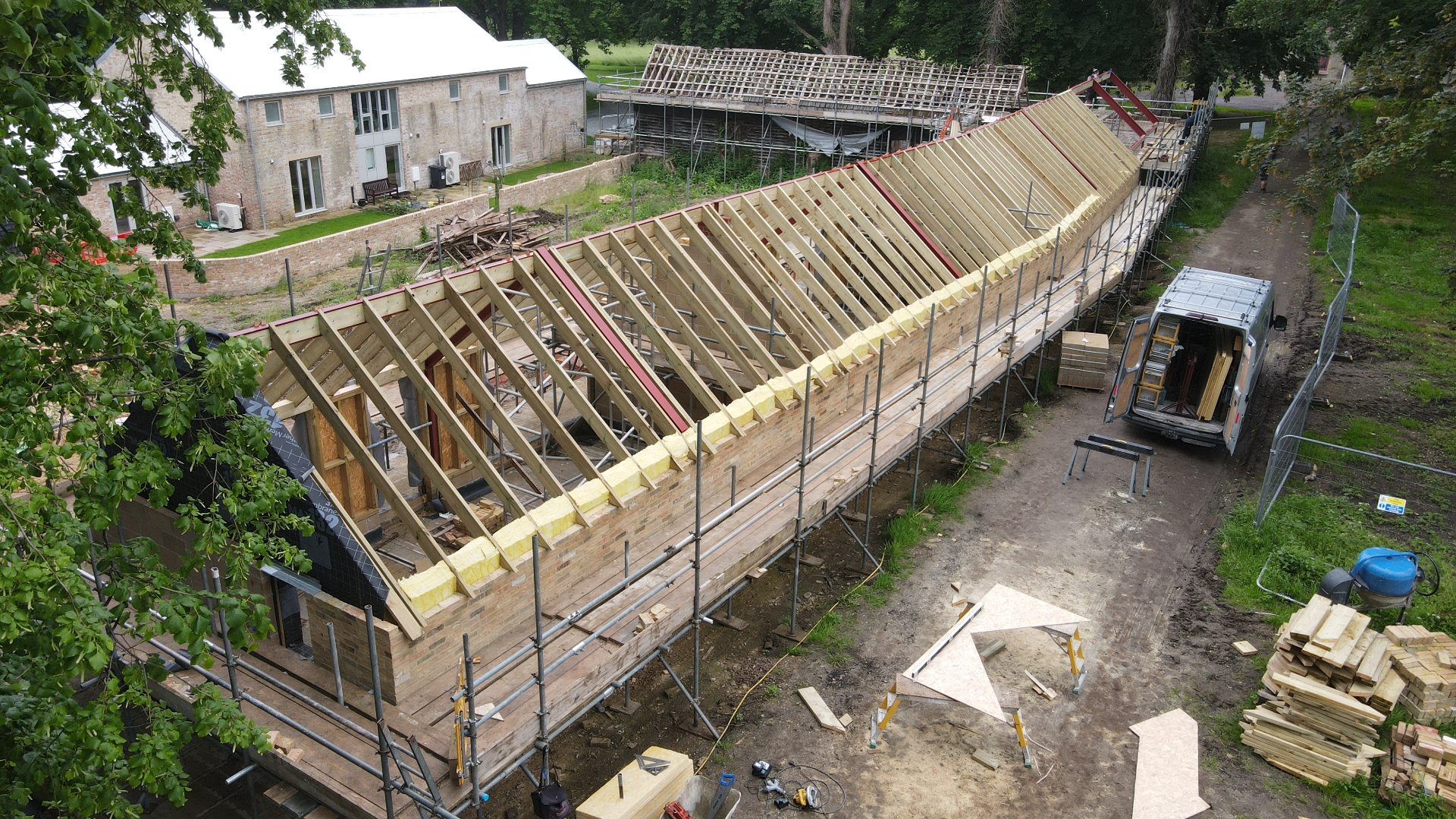 New roof timbers in place across the long stable block, scaffolding along the length of the building