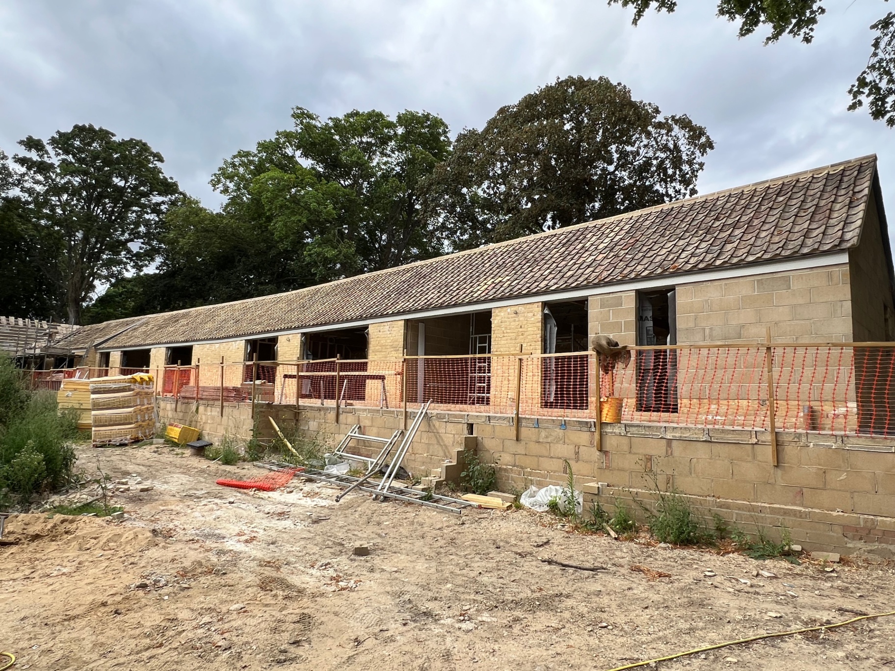 The stable block nearly finished — new tile roof on, window openings still open to the weather