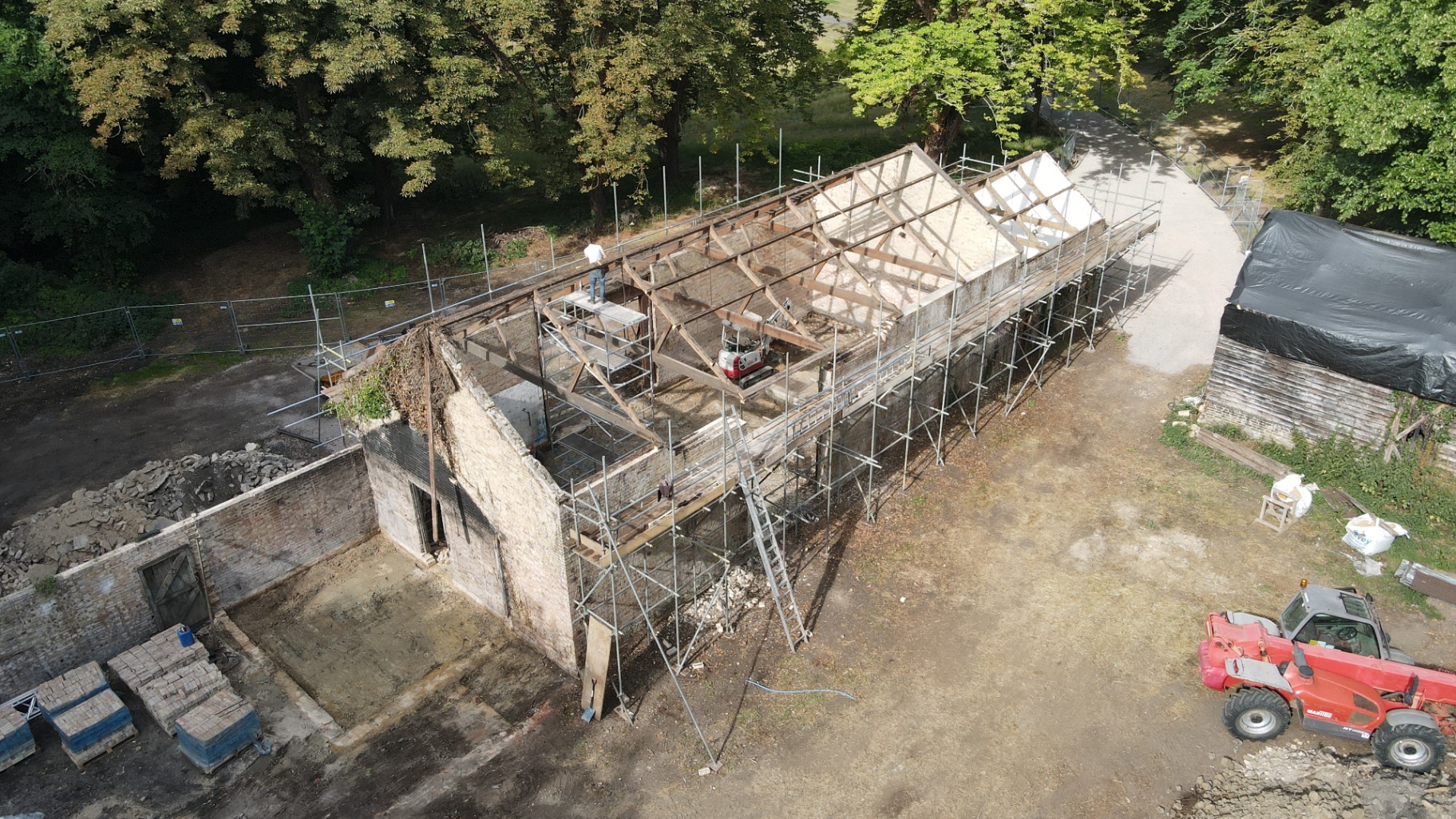 Aerial view of the parents' houses mid-construction — scaffolding around new roof timbers