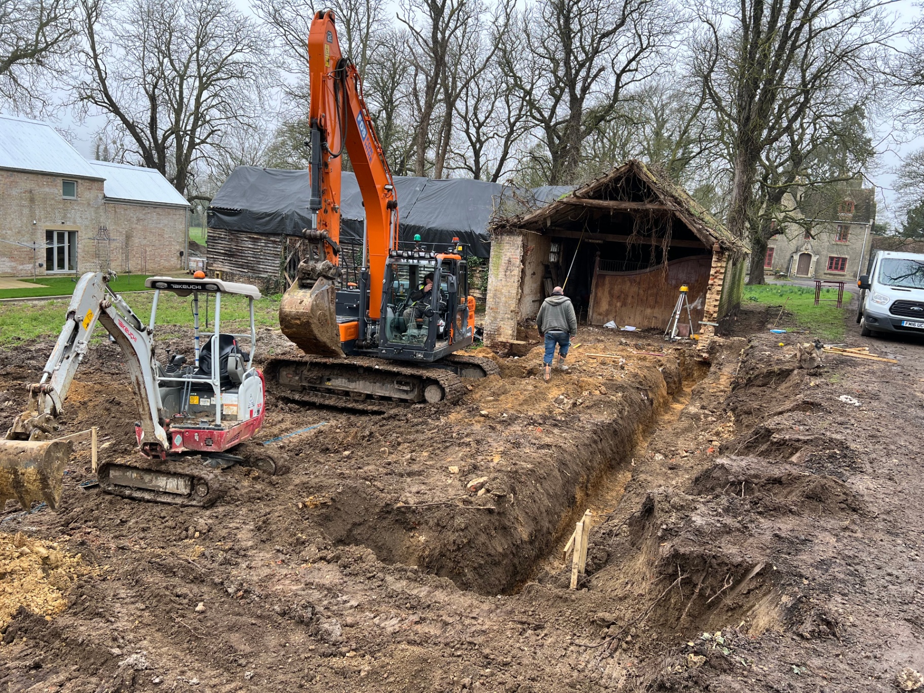 Excavators working around the old stables — walls partly demolished, foundation trenches dug
